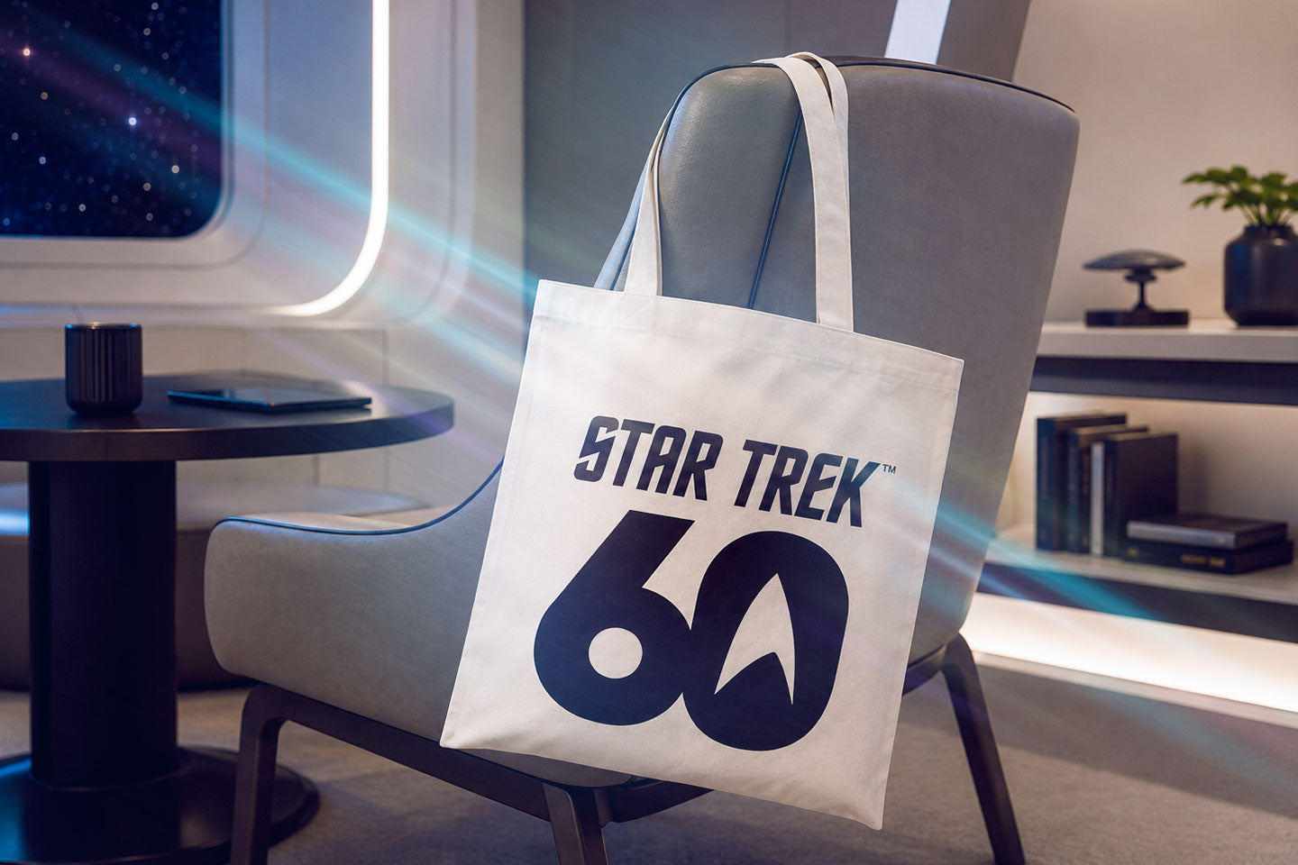 Weiße Star Trek Tragetasche zum 60. Jubiläum mit großem 60-Jahre-Motiv und Sternenflotten-Symbol, lässig über einen Sessel in futuristischer Umgebung gehängt.